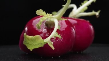 Dilimlenmiş taze turpun yakın çekimi siyah arka planda patlar. Canlı kırmızı et, karanlığa karşı bir işaret. Bu basit kompozisyon turpların eşsiz güzelliğini vurguluyor. Geliştirilebilir.