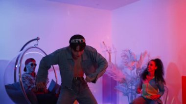 Çok kültürlü bir arkadaş kürsüde otururken Asyalı yetenekli bir dansçı modern müziğe geçiyor. Profesyonel dansçı, hipster takımı tezahürat yaparken ve desteklerken enerjik adımlar atıyor. Mutluluk.