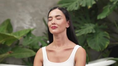 Sabah yoga ve meditasyon yapan genç bir kadın bitki yaprağıyla doğal bahçede yalnızlığın tadını çıkarıyor ve meditasyon yapıyor. Farkındalık aktivitesi ve sağlıklı zihin yaşam tarzı. Blithe