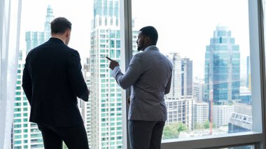 Arkaya bakan iddialı iş adamlarından oluşan farklı bir ekip süslü ofiste dikilip şehir manzarası siluetine bakıyorlar. Kararlılık ve iş hırsları kariyerlerini parlak bir geleceğe taşır.