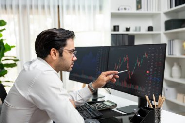 Akıllı tüccar işadamı, modern merkez ofisindeki araştırma pazarında en yüksek kârlı finansal teknolojiye yatırım yaparak bilgisayar üzerinde iki dinamik borsa yatırım ekranını analiz ediyor. Tahmin et..