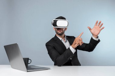 Bilgisayarla masada otururken ve VR gözlüğü takarken veri analizine bakan yetenekli bir iş adamı. Proje yöneticisi sanal gerçeklik sistemini kullanarak ya da metaevrende bağlantı kurarak çalışıyor. Sapma.