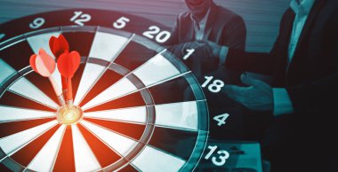 İş Hedefi Hedefi Başarı Stratejisi - Kırmızı Dart oku, arka planda çalışan iş adamlarıyla birlikte dart tahtasının ortasına isabet ediyor ve iş hedefinin başarısını gösteriyor. uds