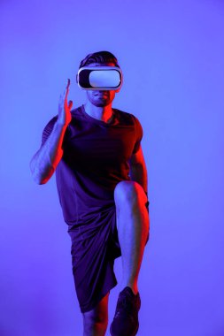 Beyaz tenli zeki bir adam neon ışıklı VR gözlük takarken koşuyor. Sanal gerçeklik kulaklığı kullanırken günlük kıyafetleri olan ya da egzersiz yapan mutlu bir insan. Yenilik teknolojisi konsepti. Sapma.