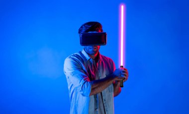 Kafkasyalı bir adam VR cam takıyor ve hareket eden el kol kılıcını tutuyor. Oyuncu, gelecekteki sanal gerçeklik kulaklığını ya da gelecekteki yenilikleri kullanarak meta dünyaya giriyor ya da aksiyon oyunu oynuyor. Sapma.