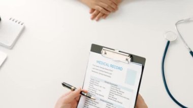 Klinikteki ya da hastane ofisindeki doktor randevusuna katılan hasta, tıbbi tedavi seçeneklerini tartışıyor ve muayene sonuçlarını ya da hastalıkla ilgili tıbbi kayıtları açıklıyor. Ağır çekim. Katı.