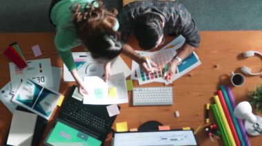 Tasarımcı yazma fikri ekrana bakarken proje yöneticisinin üst görünümü. Akıllı iş adamlarını kapat ve tasarımcı palete bakarken logo tasarımı fikrini açıkla. Sempozyum.