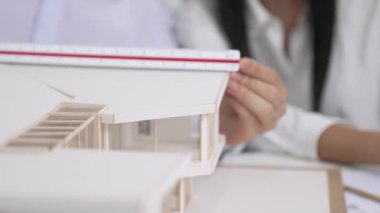 Profesyonel erkek mühendis ev modelini cetvel kullanarak ölçerken güzel bir kooperatif iş arkadaşı verileri analiz etmek için dizüstü bilgisayar kullanarak birlikte çalışıyor. Yaratıcı tasarım ve takım çalışması. - Yakın çekim. Tertemiz..