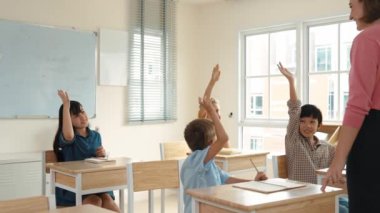Çeşitli zeki öğrenciler sınıfta çalışırken ve mutlu öğretmenleri dinlerken soruları cevaplamak için ellerini kaldırdılar. Çok kültürlü çocuklar gönüllü oldular, oy verdiler, soru sordular. Pedagoji.