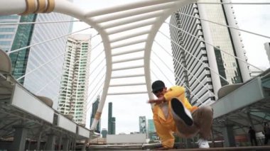 Asyalı hippi break dans çalışmasının düşük açılı kamerası ya da kulaklık takarken break dans performansı. Serbest dans, break dans, sokak dansı. Neşeli bir ruh hali. Açık hava sporu 2024. Yumuşak bir şekilde..