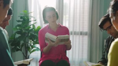 Katlanmış eller yaparken kucağında haçla İncil okuyan duaların üst görüntüsü. İnanç, güven ve umutla Tanrı 'ya dua eden farklı insanların havadan görünüşü. Ve daireler çizerek oturuyor. Sempozyum.