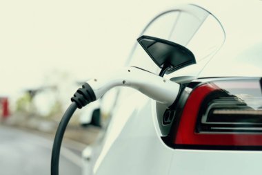 Kapalı EV şarj kolu fişe takıldı veya elektrikli arabaya bağlandı, EV araba aküsünü temiz çevre için sıfır CO2 emisyonu ile alternatif ve sürdürülebilir enerjiyle şarj etti. Kalıcı