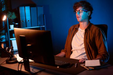 Stresli yaratıcı yönetici yeni sunumla tasarım araması yaparken ev ofisteki dizüstü bilgisayarlı ekranda gece vakti neon lambalı bir odada e-posta göndermeyi bekliyor. Toplayıcı.