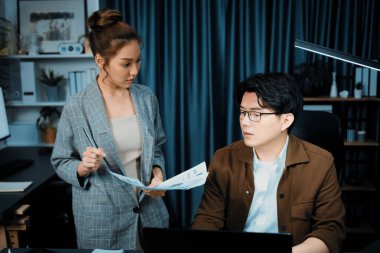 Satış müdürünün dizüstü bilgisayarında çalışan ciddi bir yüz, sekreterin gece geç saatlerde fazla mesai belgelerini verirken yönetim kurulu şirketinin veri tabanında dosya tutması için imza topluyor. İnfobahn.