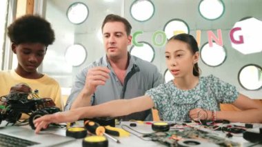 Kafkas öğrenci, öğretmene şifreyi soruyor ve bilgisayar ekranını işaret ediyor. Profesyonel eğitmen kız sorusuna cevap verirken, erkek çocuk da elektronik aletli araba modelini tamir ediyor. Öğretim