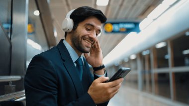 Tren istasyonunda geçmişi bulanık bir şekilde beklerken kulaklıkla müzik dinleyen zeki bir iş adamı. Yetenekli proje yöneticisi cep telefonu tutarken dinlenme sesi dinlemeyi sever. Sevinçli..