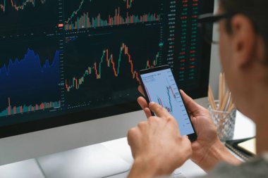 Akıllı borsa yatırımcıları ekranda akıllı telefon ile piyasa borsasını işaret ederek dizüstü bilgisayarın yanı sıra en yüksek dinamik yatırım oranını göstererek, modern işyerindeki veri planlamasına odaklanıyorlar. Bireysel.