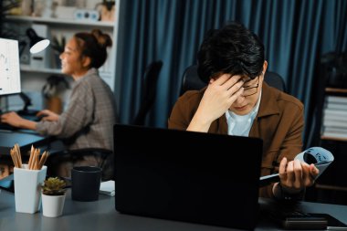 Stresli suratlı bir işadamı evrak dosyasına son teslim tarihine bakarken, aynı zamanda iş arkadaşı da gece geç saatlerde modern ofiste borsa yatırımı ticareti yapıyor. Şirket projesinde çalışıyor. İnfobahn.