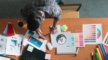 Kulaklıktan müzik dinlerken yetenekli iç dizayn grafiklerinin yukarıdan aşağı havadan görüntüsü. Proje yöneticisi kulaklıkla çalışırken ve rahat şarkılar dinlerken stüdyoda hareket ediyor. Sempozyum.