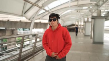 Zeki Asyalı dansçı koridorda yürürken hip hop dinler. Çekici yakışıklı hippi modern şarkıya geçiyor. Neşeli ya da mutlu olduğunu ifade et. Açık hava sporu 2024. Yumuşak bir şekilde..
