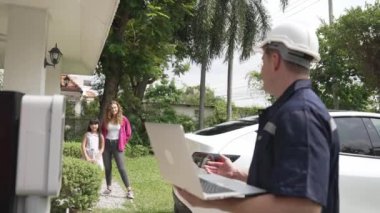 Evde EV şarj istasyonu kurulumu üzerinde çalışan nitelikli teknisyen, EV için dizüstü bilgisayarla şarj sisteminde sorun çıkarma ve yapılandırma ayarları yapıyor. Titiz