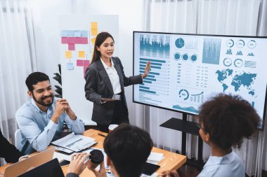 Genç Asyalı iş kadını modern toplantıda TV ekranında veri analizi paneli sunuyor. Bir grup iş adamıyla konferans odasında iş sunumu. Uyum