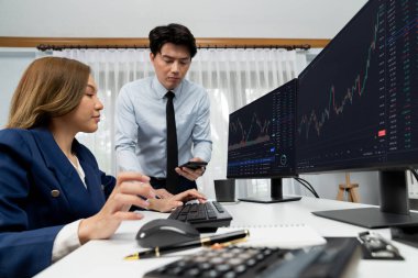 Gülümseyen işadamı cep telefonundaki dinamik borsa verilerini, iç ofisindeki internet sitesi uygulamasını analiz etmek için not yazan kadınlara gösteriyor. İnfobahn.