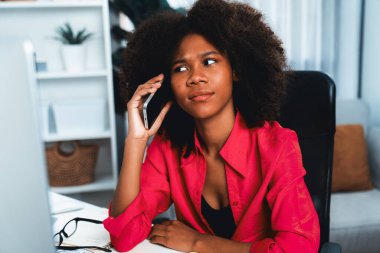 Afrikalı bir kadın telefonda iş arkadaşı ya da arkadaşıyla konuşuyor ve mutlu bir yüzle ekrana bakıyor. Şirketteki iyi haber hayatına sahip bir iş bulma konusunda başarı. Tatlandırıcı.