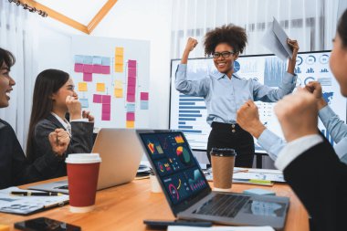 İş adamları TV ekranında başarılı bir sunum veya veri analizi toplantısından sonra kutlama yapıyorlar. Mutlu takım ofis odasında toplanıyor, kutlama jestleriyle işbirliği için tezahürat yapıyorlar. Uyum