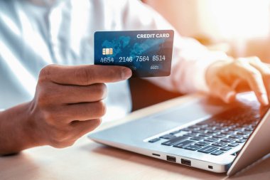 Genç adam, laptop bilgisayar başvurusu ya da web sitesinde online alışveriş yapmak için kredi kartı kullanıyor. E-ticaret ve online alışveriş konsepti. uds
