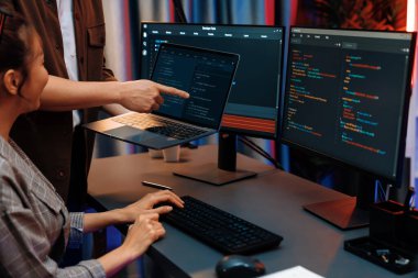 Modern ofisteki neon ışık odasında bilgi ağını gösteren dizüstü bilgisayarla iki ekranda veri çalıştıran akıllı web sitesi geliştirme kodlayıcı sistemini tartışan IT geliştiricilerinin ciddiyeti. İnfobahn.