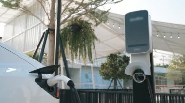 Green City Park 'taki otoparkta yavaş çekim EV elektrikli araba şarj bataryası. Sürdürülebilir ve çevre dostu şehir yolculuğu için yenilenebilir otomobil için alternatif temiz enerji teknolojisi. Yararlı