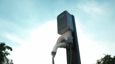 Günbatımında arka aydınlatma EV şarj istasyonu veya gündoğumu gökyüzü aydınlatması, doğal koruma için temiz ve sürdürülebilir enerjiyle çalışan gelecekteki çevre dostu ulaşımın şafağını sembolize ediyor. Yükselt