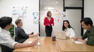 Genç liderin kapanışı, proje hakkında beyin fırtınası yapan meslektaşı ve proje yöneticisi tarafından çevrelenmiş zihin haritası ve renkli yapışkan notlar kullanılarak kendinden emin bir şekilde iş projesini sunuyor. Tertemiz..