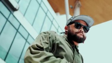 Asyalı hippi gökyüzü dövüşçüsüne dans ederken kameraya bakıyor. Modern AVM 'de düşük açılı kamerayla hip hop müziğine ayak basan çekici yakışıklı hippi. Dans edelim. Açık hava sporu 2024 hiphop..
