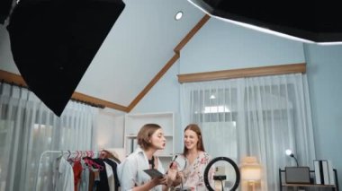 Etkilenen iki ortak canlı yayında video görüntülerini çekiyor makyaj malzemesi prim sosyal medya veya blog. Kozmetik stüdyosu ışıklandırmalı mutlu genç kız çevrimiçi pazarlama oturumu yayını için..