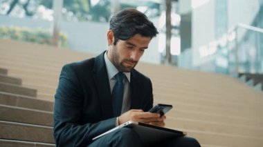 Merdivenlerde dizüstü bilgisayar ve telefon kullanarak yatırımcı çalışma ya da planlama stratejisi. Dizüstü bilgisayar kullanarak ve telefonla konuşarak veri analizi yaparken takım elbise giyen profesyonel bir iş adamı. Sevinçli..
