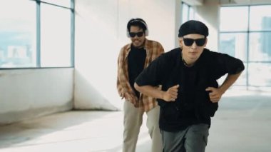 Çok kültürlü hipster grubu kameraya bakarken gökyüzü avcısıyla ya da şehir manzaralı bir binada break dans yapıyorlar. Sokak dansçısı ekibi dansçı performansına bakıyor. Açık hava sporu 2024 hiphop..