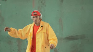 Beyaz hipster sokak, şehir merkezinde ayak sesleri gösteriyor ya da pratik yapıyor. Break dansçı, kulaklıktan müzik dinlerken hip-hop müziğine adım atıyor. Açık hava sporu 2024. Gri arka plan. hiphop.