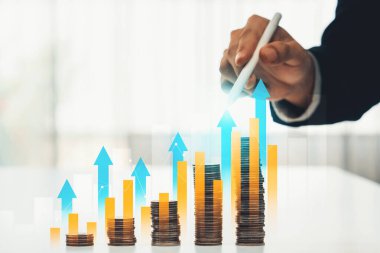 Dijital grafik göstergeli bozuk para yığını iş yatırımını ve ekonomik büyümeyi sembolize ediyor. Finansal hedefe ulaşmak ve kâr sağlamak için finansal planlama yapan bir iş adamı. Kurnaz.