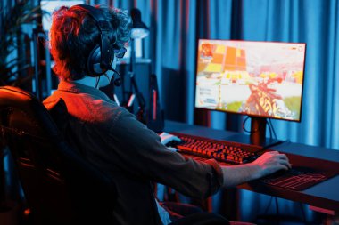 Genç oyun flamasının sunucu kanalı, takım oyuncusu, dijital neon odasında mikrofonlu kulaklık takarak bilgisayar ekranında çoklu oyuncuyla savaş oyunu oynuyor. Toplayıcı.