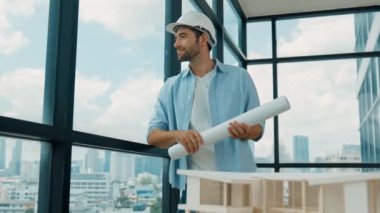 Gökdelen manzarasına bakarken yürüyen profesyonel mimar mühendisi. Masaya yerleştirilmiş ev modeliyle pencereye bakarken yetenekli proje yöneticisi proje planını tutuyor. Tasarım. İzleme