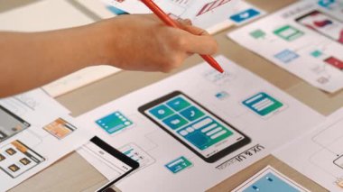 Girişimci şirket çalışanının el odaklı hali ofis çalışma alanındaki akıllı yöneticiye mobil uygulama için kullanıcı arayüzü prototipi sunar. UX UI tasarımcısı kağıt üzerinde simge tasarımının işlevini açıklıyor. Sinerjik