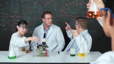 Zeki öğretmen, öğrenci renkli çözeltileri karıştırırken ya da deney yaparken kimyasal teoriyi açıklar. BTMM fen dersinde karatahtaya işaret ederken, eğitmen kimya öğretiyor. Öğretim