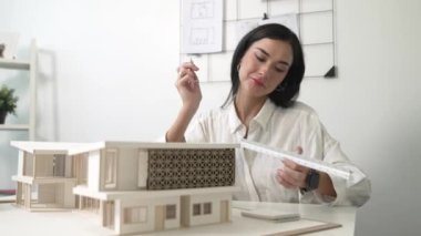 Profesyonel mühendis mimarın üçgen ölçekli ölçü evi modelini kullanarak modern ofisteki yapı uzunluğunu not alarak yakınlaşması. İş tasarımı. Tertemiz..
