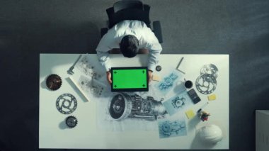 Türbin motor çizim tasarımı, metal teçhizat ve mimari ekipmanlar etrafa saçılmış yeşil ekranı incelerken kağıt üzerine yazı yazan yetenekli mühendisin üst görünümü. Hizalama.