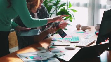 Akıllı tasarımcının renkli paletlerden renk seçmesine yardım ederken yukarıdan aşağı görünümü. Dizüstü bilgisayardan logoya bakarken birlikte çalışan ve planlayan iş adamlarının hava görüntüsü. Sempozyum.