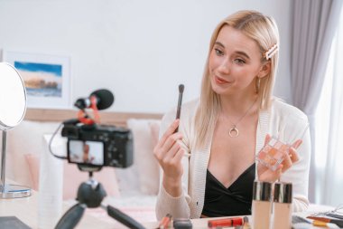 Sosyal medya için güzellik ve kozmetik video içeriği hazırlayan genç bir kadın. Güzellik blogcusu kameraya gülümserken seyircilere ve takipçilere güzellik bakımını gösteriyor. Blithe