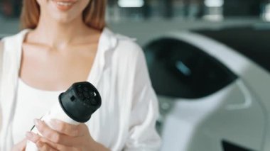 Yavaş çekim kadın, EV elektrikli arabasıyla şehir merkezindeki alışveriş merkezinin otoparkına gidiyor. Sürdürülebilirlik yaşam tarzını yeşil, temiz, yeniden şarj edilebilir elektrikli araç iç organlarıyla şarj ediyor.