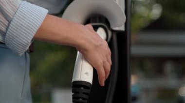 Otomobil seyahati sırasında elektrikli araba için şarj olan kadın Autumanl sezonunda doğal orman ya da milli parkta. Tatil ve tatil boyunca çevre dostu seyahat. Yükselt